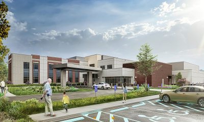 Image of a building with windows, and trees and parking in front
